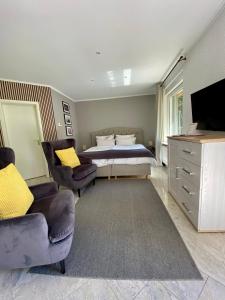 a bedroom with a bed and two chairs and a television at Bungalow Saaletal in Kahla