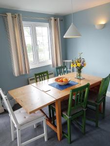 een eettafel met groene stoelen en een houten tafel bij 1 Bell Lodge, Thorpeness in Thorpeness