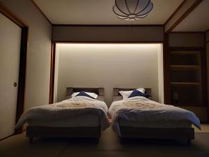 2 camas en una habitación con ventana grande en Tsukimotoya Ryokan en Toyooka