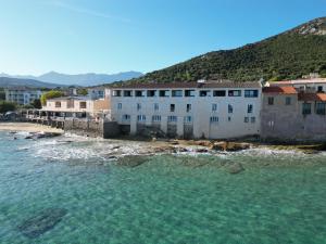 un groupe de bâtiments sur une plage au bord de l'eau dans l'établissement Hotel Beau Rivage, à Algajola