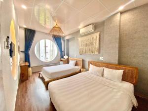 een hotelkamer met 2 bedden en een raam bij Hue Sweethouse 1 Homestay in Hue