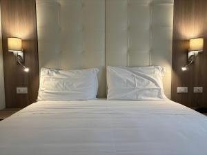 a large bed with white sheets and pillows at Hotel Boccascena in Genoa