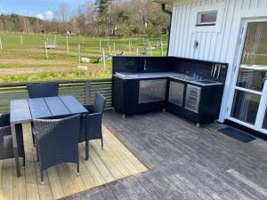 a deck with a table and chairs and a kitchen at Skedala horsefarm in Halmstad