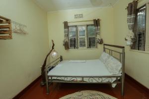 Cama pequeña en habitación con ventana en Janibichi Adventures hostel en Moshi