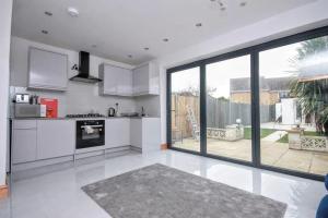 a kitchen with white appliances and a large window at Beautiful Bright Three Bedroom House in Brighton and Hove with free parking in Portslade