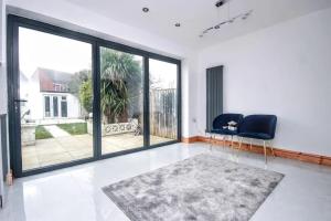 ein Wohnzimmer mit einem Stuhl und einem großen Fenster in der Unterkunft Beautiful Bright Three Bedroom House in Brighton and Hove with free parking in Portslade