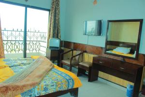 a bedroom with a bed and a dresser and a mirror at Mount Heaven Hotel Murree in Murree