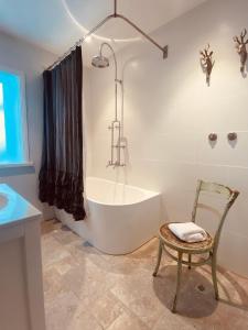 ein Badezimmer mit einer Badewanne und einem Stuhl in der Unterkunft Illalangi Boutique Cottage in Blackheath