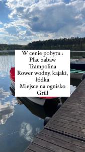 un cartello seduto su un molo accanto a un corpo d'acqua di Domki Letniskowe Nad Jeziorem Kazub a Cieciorka