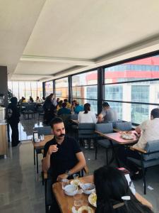 un grupo de personas sentadas en mesas en un restaurante en world say hotel, en Bostaniçi