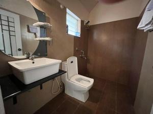 a bathroom with a white toilet and a sink at Cocoon Earth Home - Pool Villa Kovalam in Kovalam