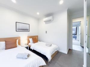 two beds in a room with white walls at Modern 3-level Townhouse FreeParking in Melbourne