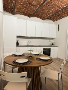 - une cuisine avec une table en bois et des placards blancs dans l'établissement Le Corti, à Coni