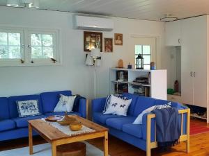 - un salon avec des canapés bleus et une table en bois dans l'établissement Holiday home MARIEFRED IX, à Mariefred
