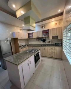 a large kitchen with wooden cabinets and a counter top at Villa duplex meublée piscine à Akpakpa ciné concorde in Cotonou