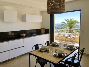 a kitchen and dining room with a table with chairs at Appartement T3 lumineux traversant totalement neuf en face de la plage Front de mer vue sur les iles Vue mer panoramique assurée Résidence de la plage centre ville du Lavandou 3eme étage avec ascenseur Appartement T3 in Le Lavandou