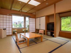 - un salon avec une table, des chaises et une télévision dans l'établissement KKR Yuzawa Yukiguni, à Yuzawa