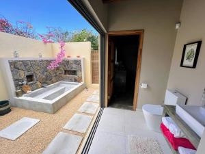 a bathroom with a tub and a stone wall at Lakaz Kannell - Room 2 - Turtle Lodge, secluded outside bath & shower infinity pool in Cap Malheureux