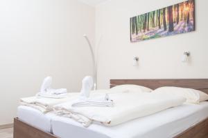 ein Schlafzimmer mit einem weißen Bett und einem Gemälde an der Wand in der Unterkunft Relax & Therapy in Bad Tatzmannsdorf