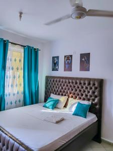 a bedroom with a large bed with blue curtains at Dasha Studio apartment Bamburi D4 in Bamburi