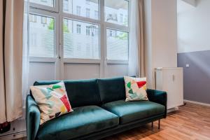 a green couch in a living room with windows at Spacious, central 3 room flat with gym & play area in Berlin