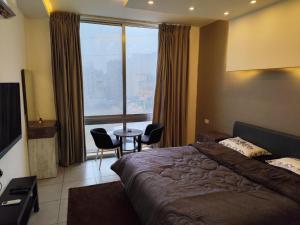 a bedroom with a large bed and a table with chairs at Gentle Breeze Studio1 in Amman
