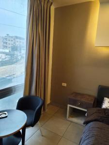 een kamer met een bed, een tafel en een raam bij Gentle Breeze Studio1 in Amman