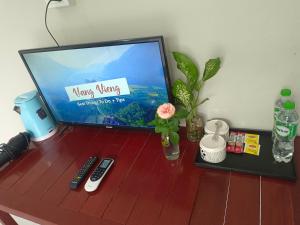 una televisione seduta su un tavolo di legno con telecomando di Dokchampa Hotel a Vang Vieng