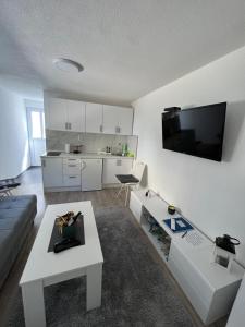 uma sala de estar com um sofá e uma televisão na parede em Apartman Milica em Trebinje