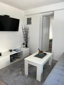 sala de estar blanca con mesa blanca y TV en Apartman Milica, en Trebinje
