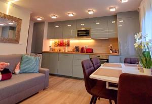 a living room with a couch and a table and a kitchen at Dénár Apartmanház in Veresegyház