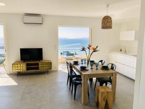 a kitchen and dining room with a table and a television at T3 FRONT de mer dernier étage vue mer Petit havre de paix pour vos vacances Emplacement unique vue mer panoramique à 180 degrés pour ce T3 en face de la plage front de mer vue sur les iles 5 et dernier étage avec ascenseur in Le Lavandou