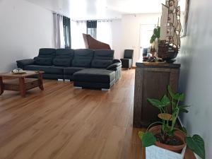uma sala de estar com um sofá preto e um piso de madeira em Residência Águia em Praia