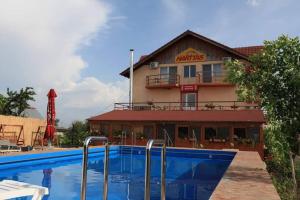 a hotel with a swimming pool in front of a building at Pensiunea HARTTAS in Maliuc
