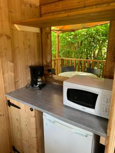 una cocina con microondas en una barra en una cabaña en Camping La Saline d'Arc et Senans, en Arc-et-Senans
