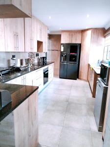 a kitchen with wooden cabinets and a black refrigerator at Reutlwane Gardens house in Secunda