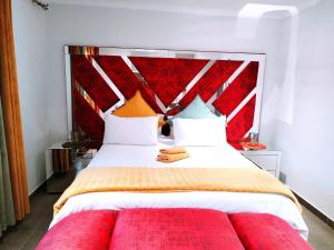 a bedroom with a large bed with a red headboard at Reutlwane Gardens house in Secunda