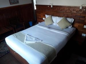 uma cama grande com lençóis brancos e almofadas em Dragon Hotel em Pokhara