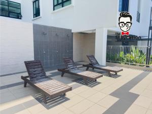 3 chaises assises sur une terrasse en face d'un bâtiment dans l'établissement Staycation Homestay 44 Gem Suite, à Kuching