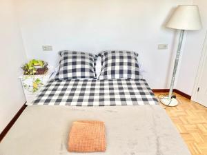 a bed with two black and white pillows and a lamp at La Casa de los Libros in Muros de Nalón