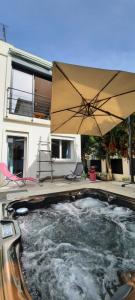 a hot tub with an umbrella in front of a house at Villa SPA Hyères 6 personnes au calme in Hyères +8 photos
