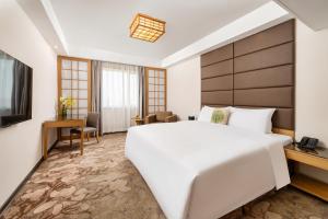 um quarto com uma grande cama branca e uma televisão em GuangDong Hotel Shanghai em Xangai