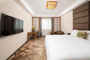 上海市にある広東 ホテル 上海のベッドとテレビが備わるホテルルームです。