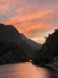 a view of a river at sunset with mountains at Riverside Komani Lake in Koman