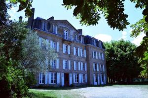 a large brick building with trees in front of it at Chambre d'hôtes chez Johannes et Adèle in Brive-la-Gaillarde