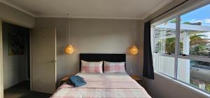 um quarto com uma cama e uma grande janela em Miami Stay em Auckland