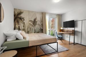 a bedroom with a bed and a desk and a television at Jungle Deluxe Suite - Parken Balkon Jumanji TV in Offenbach