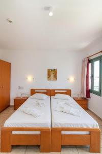 Duas camas num quarto com paredes brancas em Ageri Hotel em Tinos Town