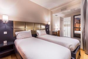2 Betten in einem Hotelzimmer mit weißer Bettwäsche in der Unterkunft Hotel Jenner in Paris