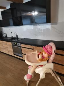 una muñeca sentada en una trona en una cocina en Chatka Katka en Oravska Jasenica
